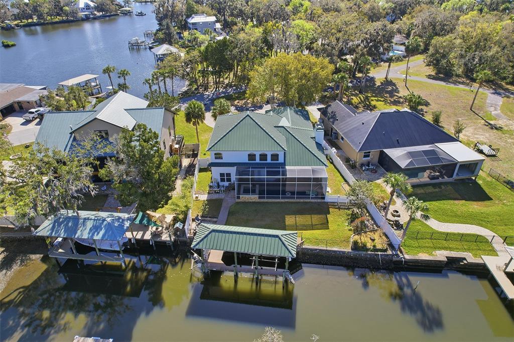 An aerial view shows three waterfront houses with green metal roofs and private boat docks — 300 NW 12TH AVENUE, CRYSTAL RIVER, FL