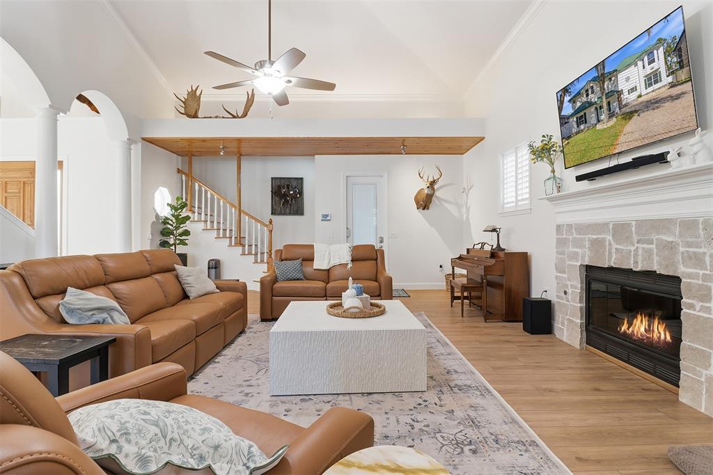 A living room features leather sofas, a stone fireplace, a piano, and a wooden staircase — 300 NW 12TH AVENUE, CRYSTAL RIVER, FL
