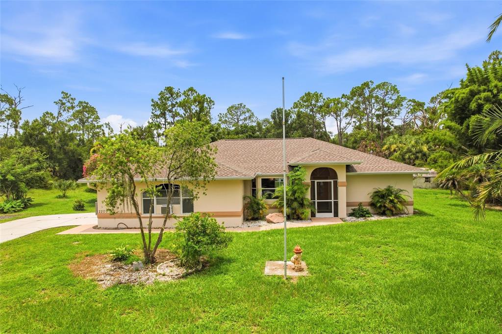 A single-story house with a beige exterior, a shingled roof, and a front yard lawn — 2209 TROPICAIRE BOULEVARD, NORTH PORT, FL