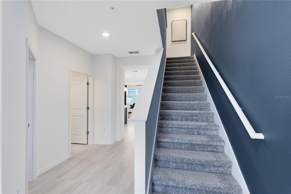 An interior view shows a carpeted staircase with a blue wall next to a hallway — 4560 ORCHARD VIEW ALLEY, CLERMONT, FL