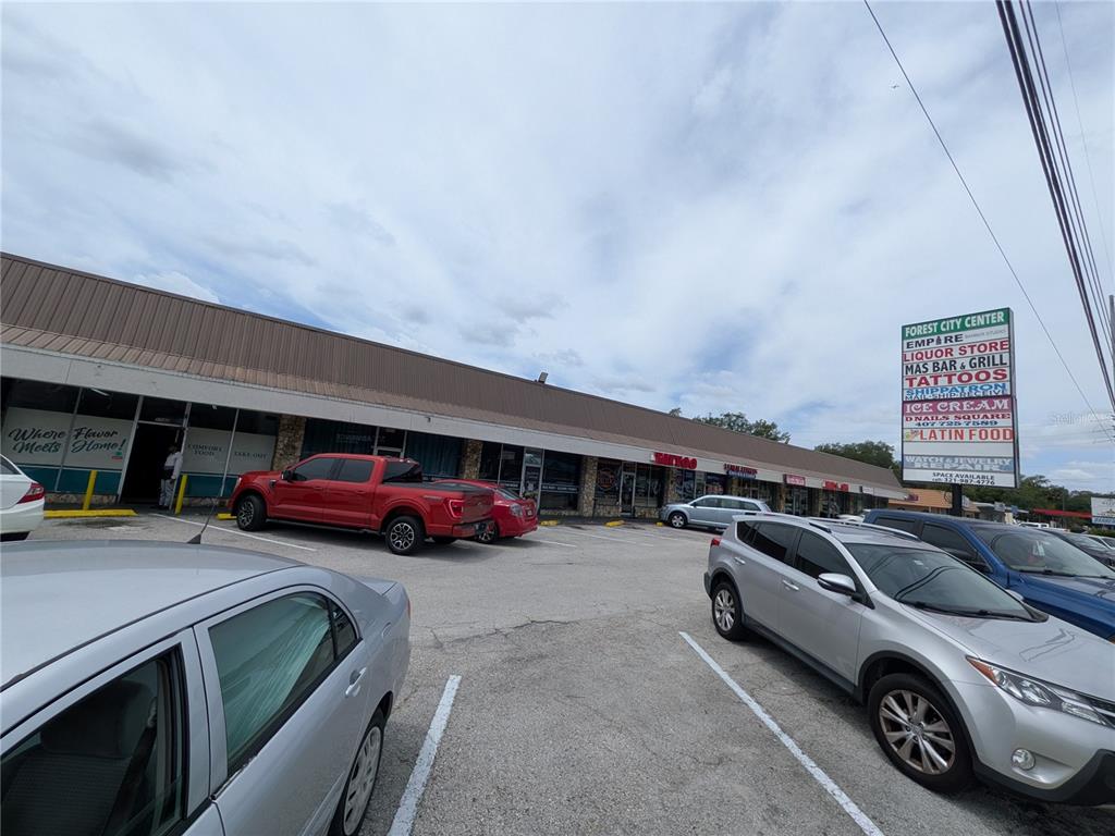 A strip mall features a parking lot in front of several storefronts under a brown awning — 1160 W STATE ROAD 436 UNIT 1150, ALTAMONTE SPRINGS, FL