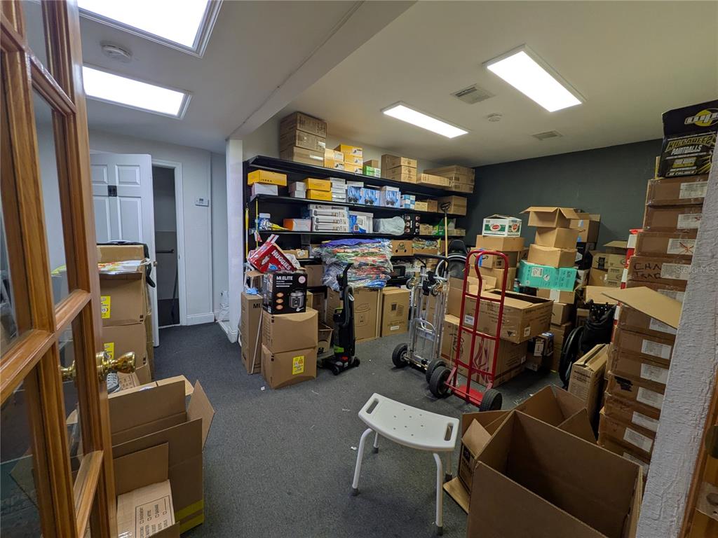 A cluttered storage room features gray carpeting, recessed lighting, and numerous cardboard boxes and shelving — 1160 W STATE ROAD 436 UNIT 1150, ALTAMONTE SPRINGS, FL