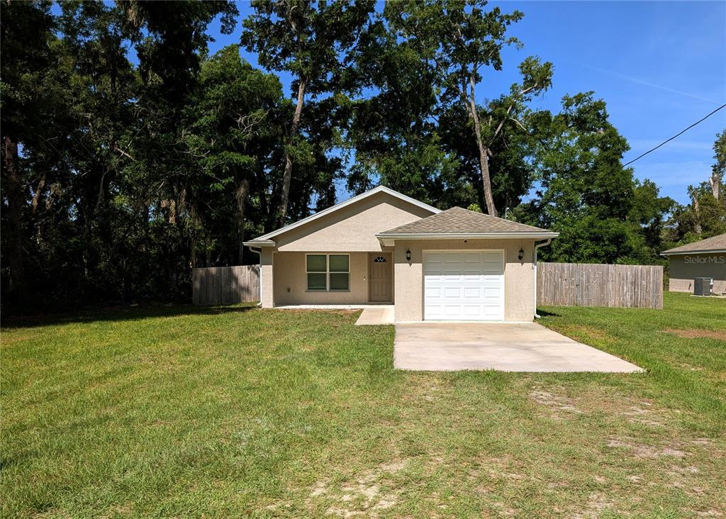 A single-story house with a beige stucco exterior, a one-car garage, and a front lawn — 13296 SE 33RD COURT, BELLEVIEW, FL