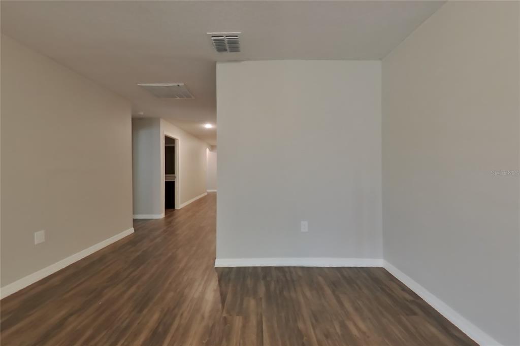 An interior view shows a room with light gray walls and dark wood-look flooring — 1744 CHATHAM GREEN CIRCLE, RUSKIN, FL