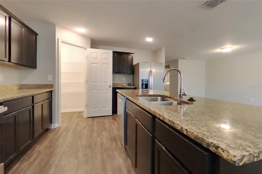 A kitchen features dark wood cabinets, granite countertops, a center island, and a walk-in pantry — 1744 CHATHAM GREEN CIRCLE, RUSKIN, FL