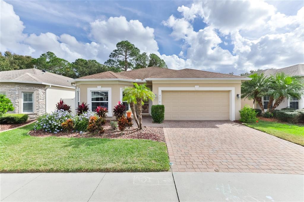 A single-story house with a beige stucco exterior, a two-car garage, and a landscaped yard — 3849 BOURBON STREET, PORT ORANGE, FL