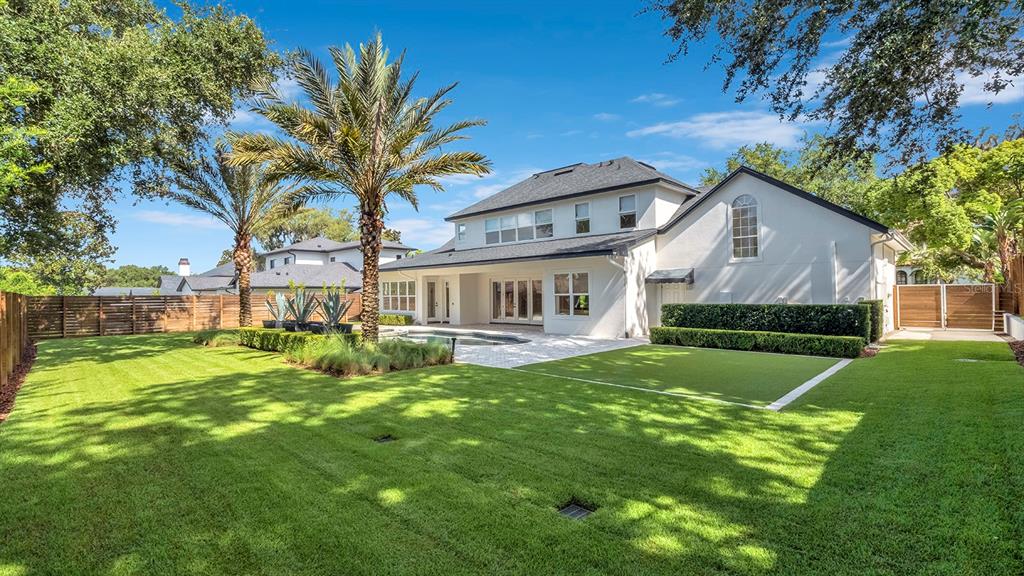 The backyard features a swimming pool, a manicured lawn, palm trees, and a white house — 948 POINCIANA LANE, WINTER PARK, FL