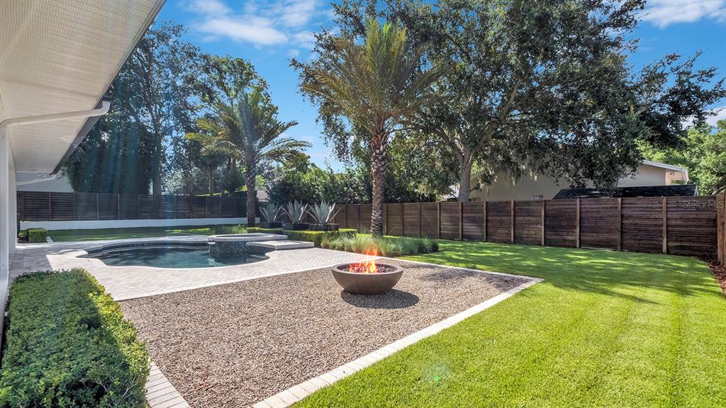 A backyard features a swimming pool, a fire pit, a lawn, and a wooden fence — 948 POINCIANA LANE, WINTER PARK, FL