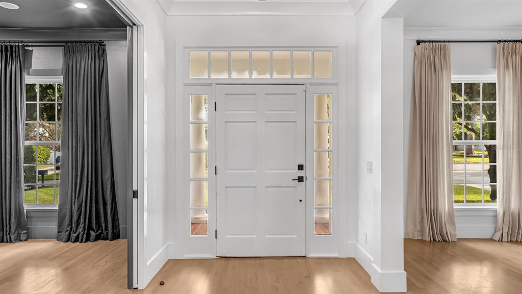 A bright entryway features a white front door with sidelights, transom windows, and hardwood floors — 948 POINCIANA LANE, WINTER PARK, FL