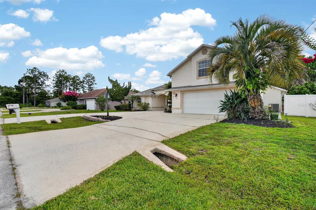 A two-story house with a white garage, concrete driveway, and a palm tree in front — 11 ZONAL GERANIUM COURT, PALM COAST, FL