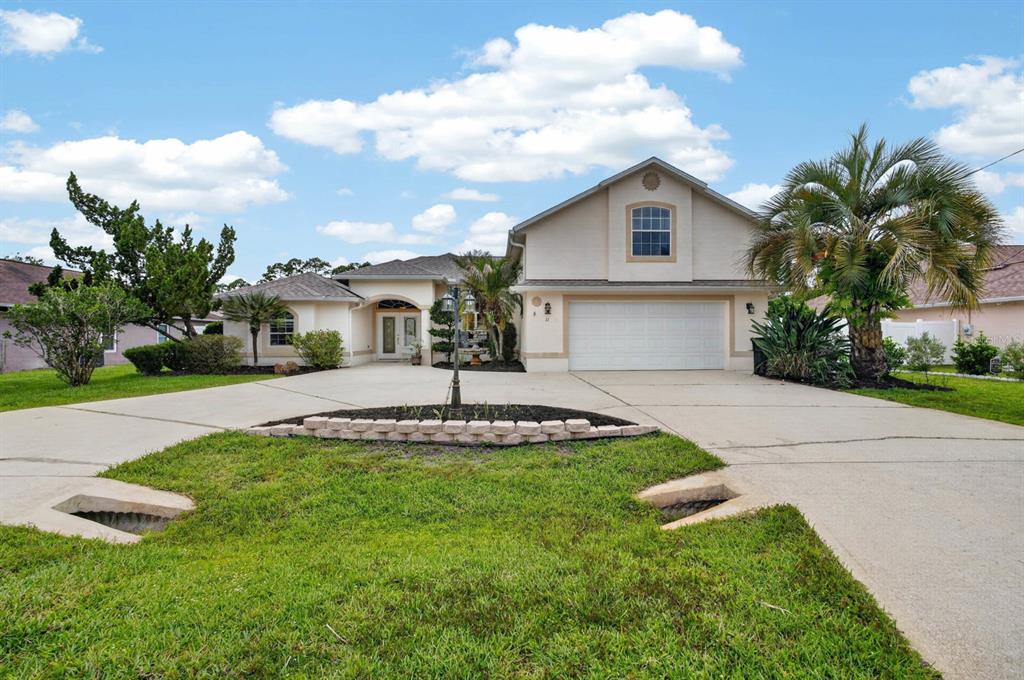 A single-story house with a two-car garage, a paved driveway, and a landscaped front yard — 11 ZONAL GERANIUM COURT, PALM COAST, FL