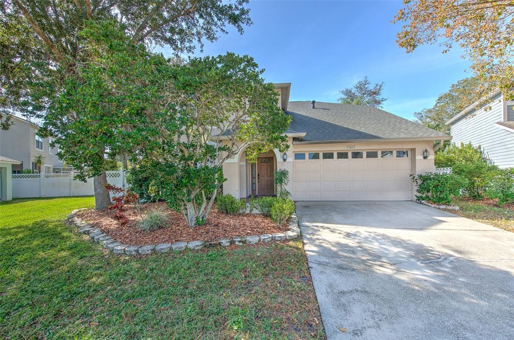 A two-story house with a beige stucco exterior, a two-car garage, and a landscaped front yard — 9205 CELEBRATION COURT, TAMPA, FL