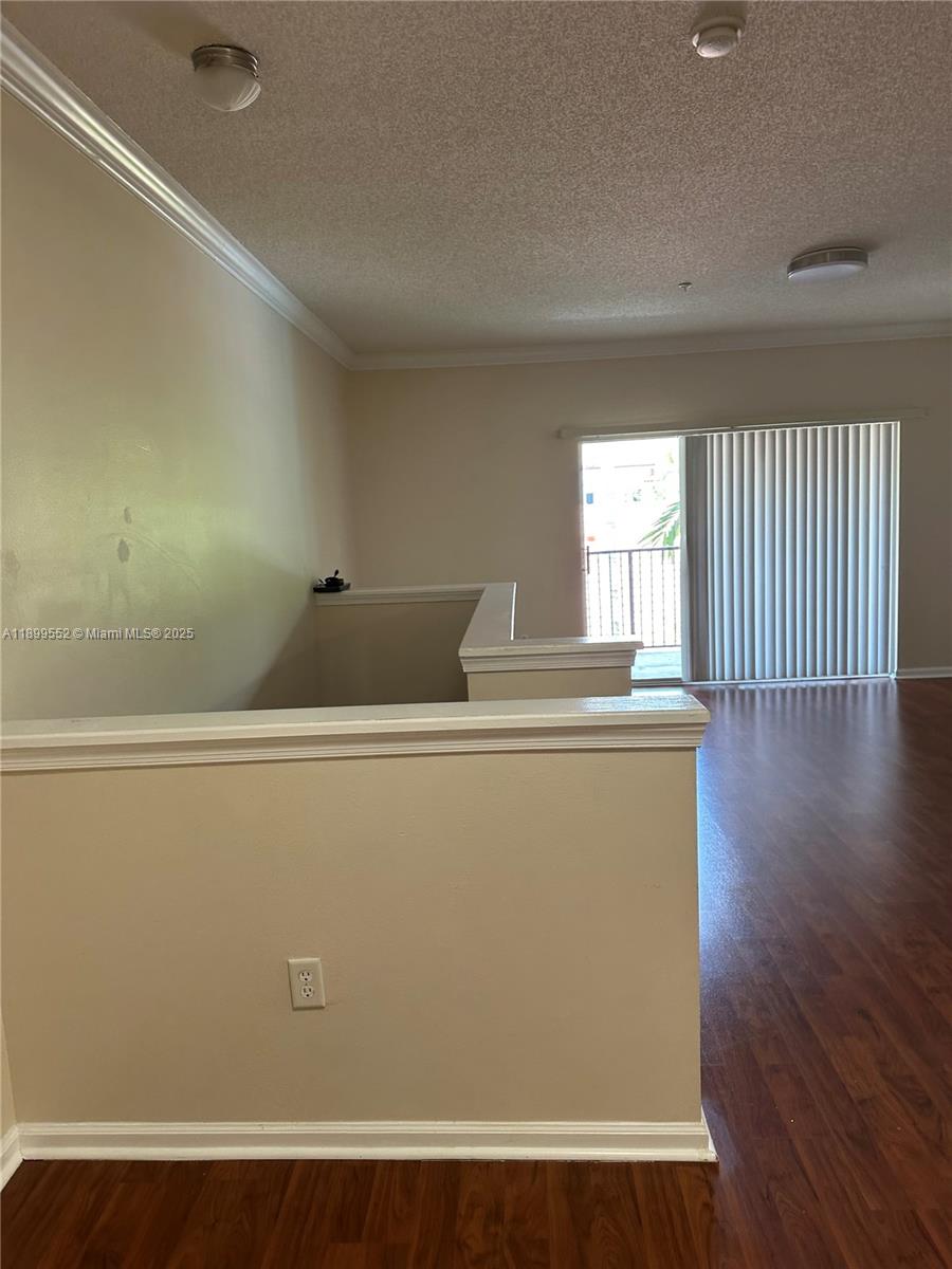 This interior view shows a living area with wood-look flooring and a balcony door — 5840 W Sample Rd # 306, Coral Springs FL 33067, CORAL SPRINGS, FL