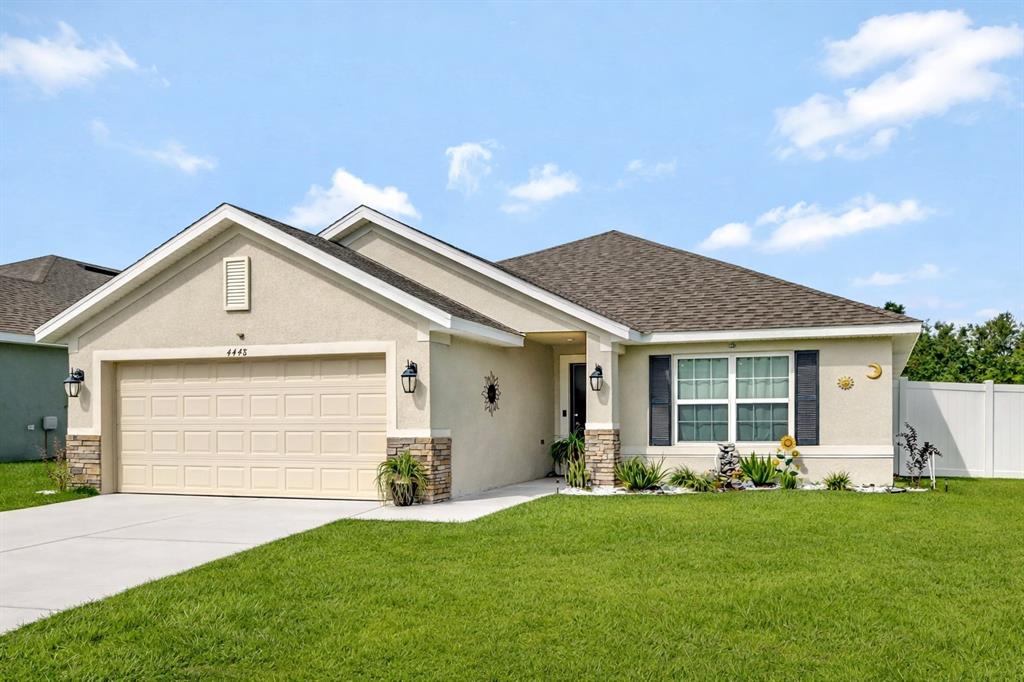 A single-story house with a beige stucco exterior, stone accents, and a two-car garage — 4448 NW 2ND COURT, OCALA, FL