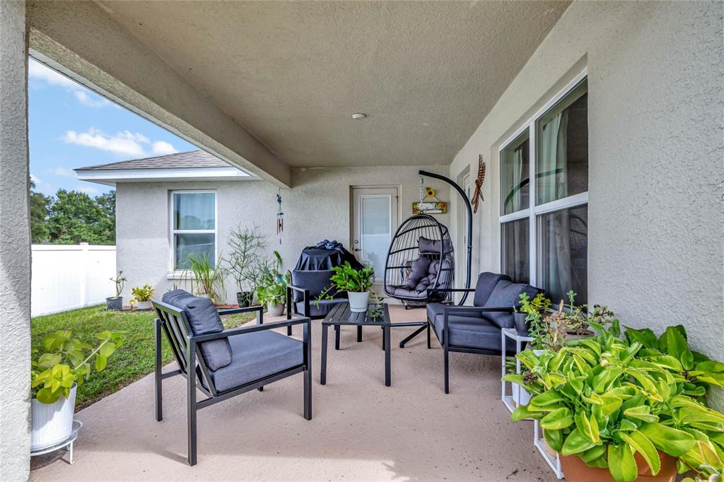 A covered patio features outdoor furniture, potted plants, and a view of a fenced yard — 4448 NW 2ND COURT, OCALA, FL