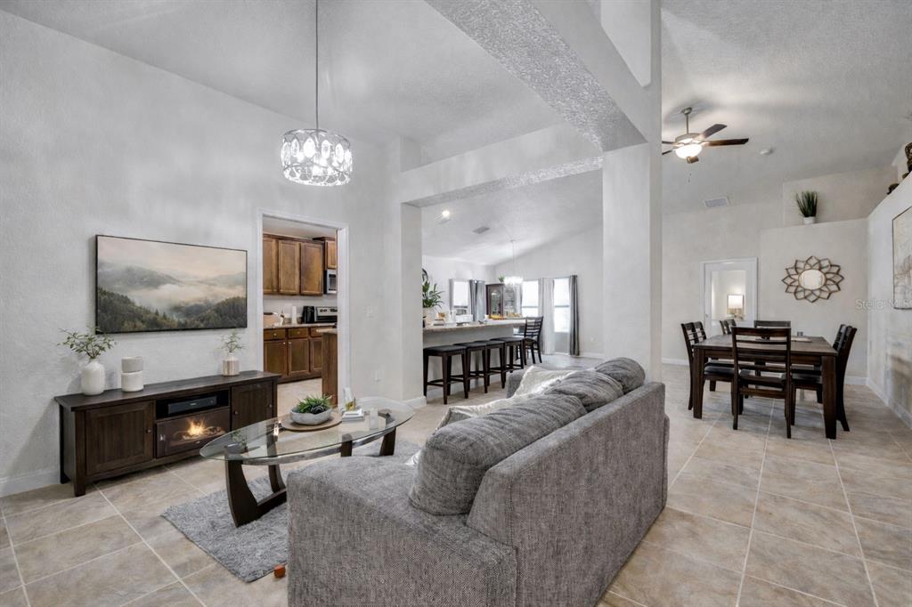 An open-concept living room with tile flooring, a gray sofa, and a dining area — 4448 NW 2ND COURT, OCALA, FL