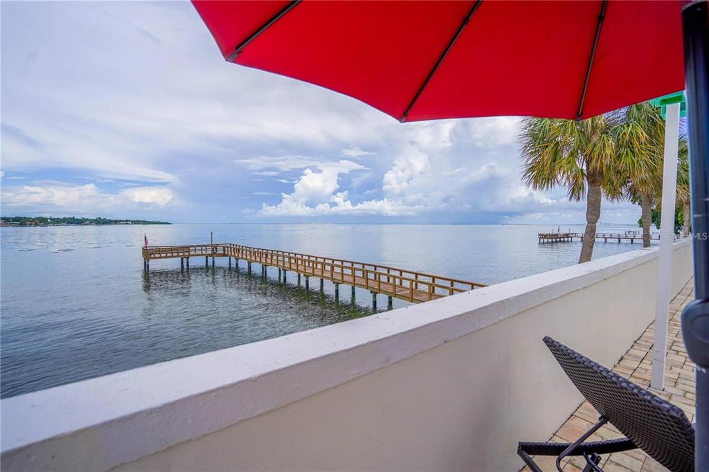 A view from a balcony overlooking a wooden pier extending into a calm bay — 7100 SUNSHINE SKYWAY LANE S UNIT 201, ST PETERSBURG, FL