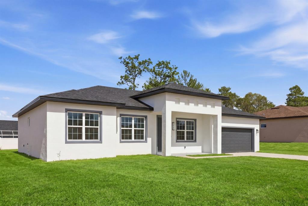 A single-story house with white stucco walls, a dark roof, and an attached garage — 4487 SW 152 STREET, OCALA, FL