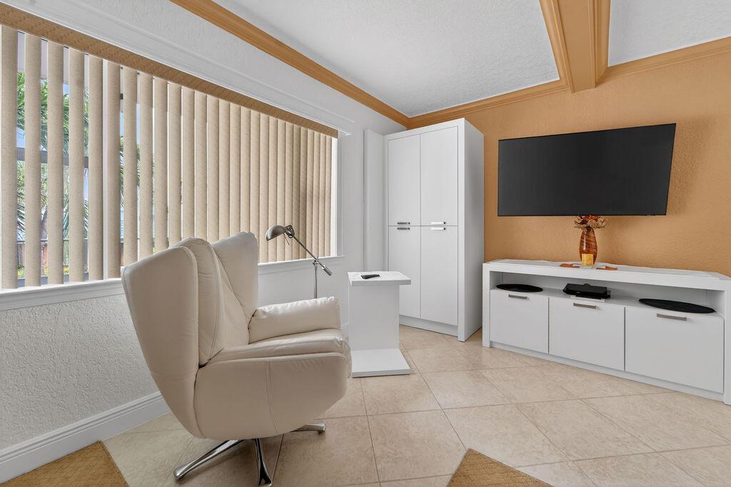 A living room features a white armchair, a television, a white cabinet, and vertical blinds — 3200 NE 7th Court Unit 201a, Pompano Beach FL 33062, POMPANO BEACH, FL
