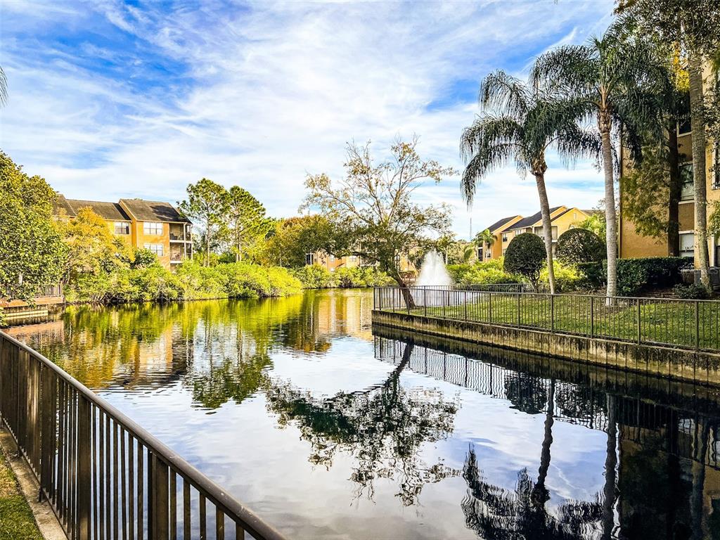 A view of a pond with a fountain surrounded by apartment buildings and palm trees — 11901 4TH STREET N UNIT 8102, ST PETERSBURG, FL