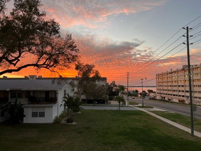 An exterior view of a residential building and a multi-story apartment complex at sunset — 2944 W BAY DRIVE UNIT 201, BELLEAIR BLUFFS, FL