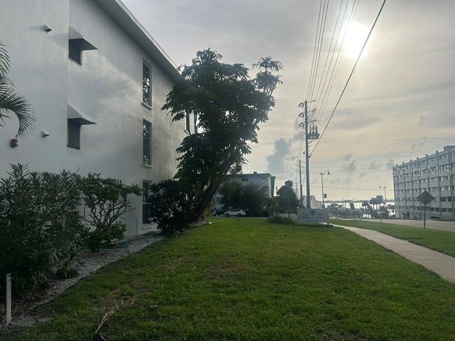 A side view of a white apartment building next to a grassy lawn and sidewalk — 2944 W BAY DRIVE UNIT 201, BELLEAIR BLUFFS, FL