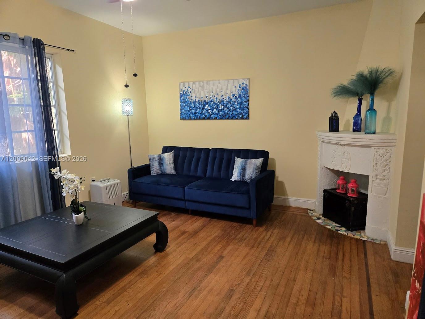 A living room features a blue sofa, a black coffee table, and a decorative fireplace — 1219 Meridian Ave # 2, Miami Beach FL 33139, MIAMI BEACH, FL