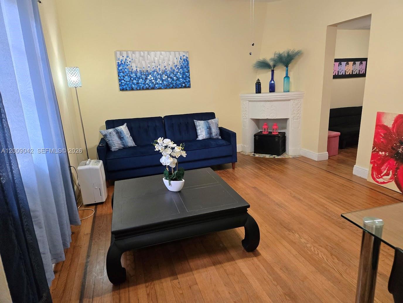 A living room features a blue sofa, a black coffee table, and a decorative fireplace — 1219 Meridian Ave # 2, Miami Beach FL 33139, MIAMI BEACH, FL