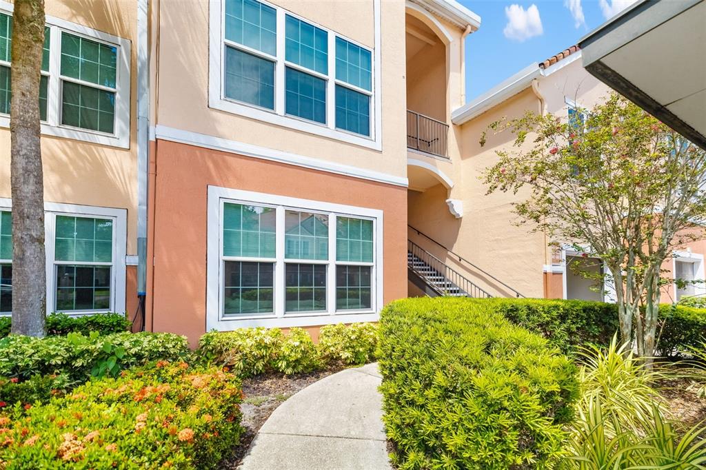 A concrete walkway leads to the entrance of a two-story apartment building with stucco walls — 4142 CENTRAL SARASOTA PARKWAY UNIT 1415, SARASOTA, FL