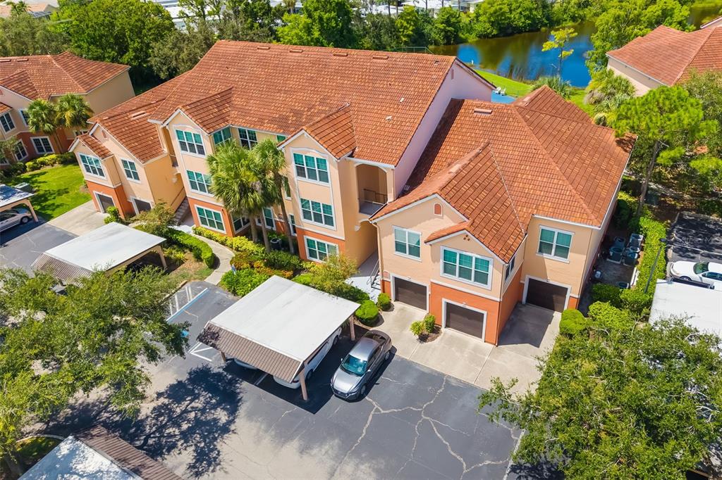 A three-story apartment building with tan stucco walls, palm trees, and a parking lot — 4142 CENTRAL SARASOTA PARKWAY UNIT 1415, SARASOTA, FL
