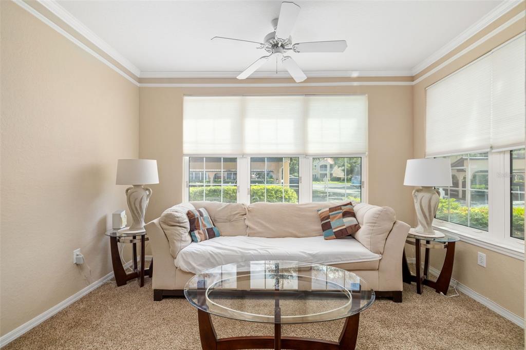 A living room with beige walls, carpet, a white sofa, and a glass coffee table — 4142 CENTRAL SARASOTA PARKWAY UNIT 1415, SARASOTA, FL