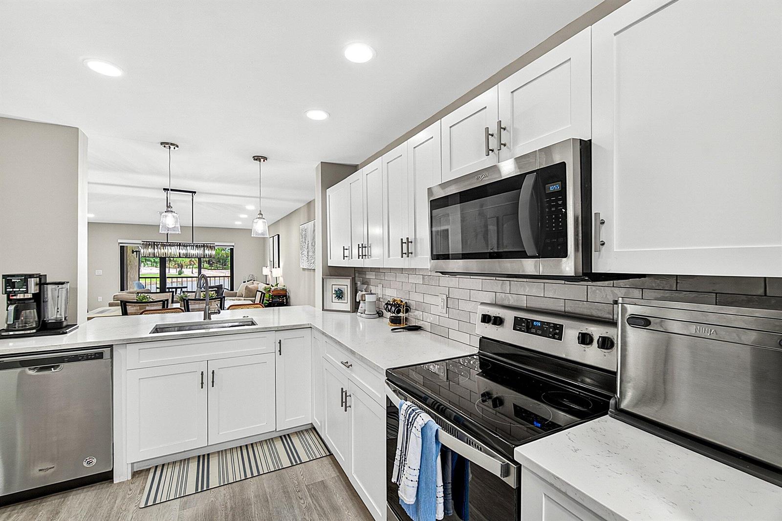 A modern kitchen features white cabinets, stainless steel appliances, and a gray subway tile backsplash — 35 Southport Lane # D, Boynton Beach FL 33436, BOYNTON BEACH, FL