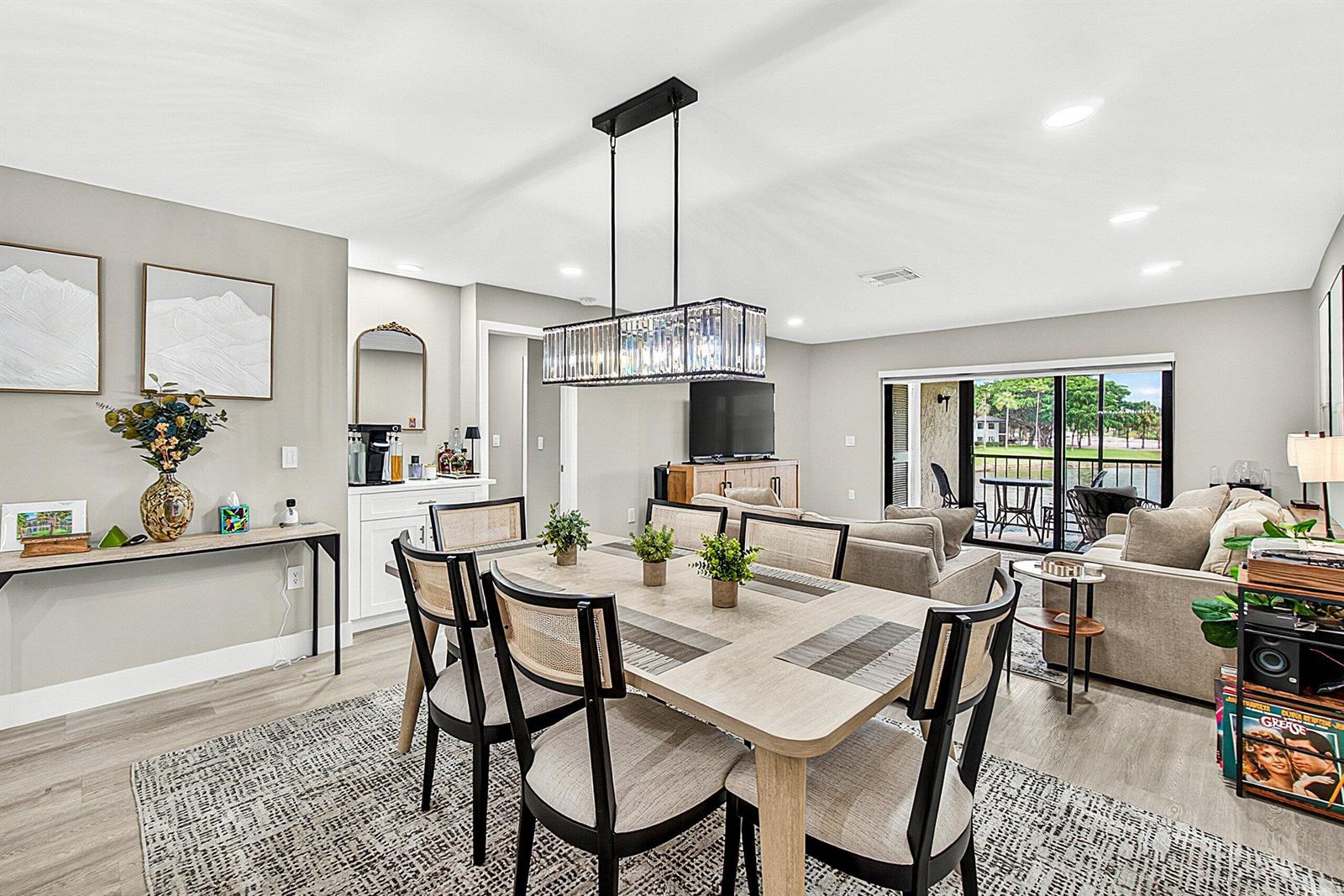 A dining area with a rectangular table and crystal chandelier opens to a living room — 35 Southport Lane # D, Boynton Beach FL 33436, BOYNTON BEACH, FL
