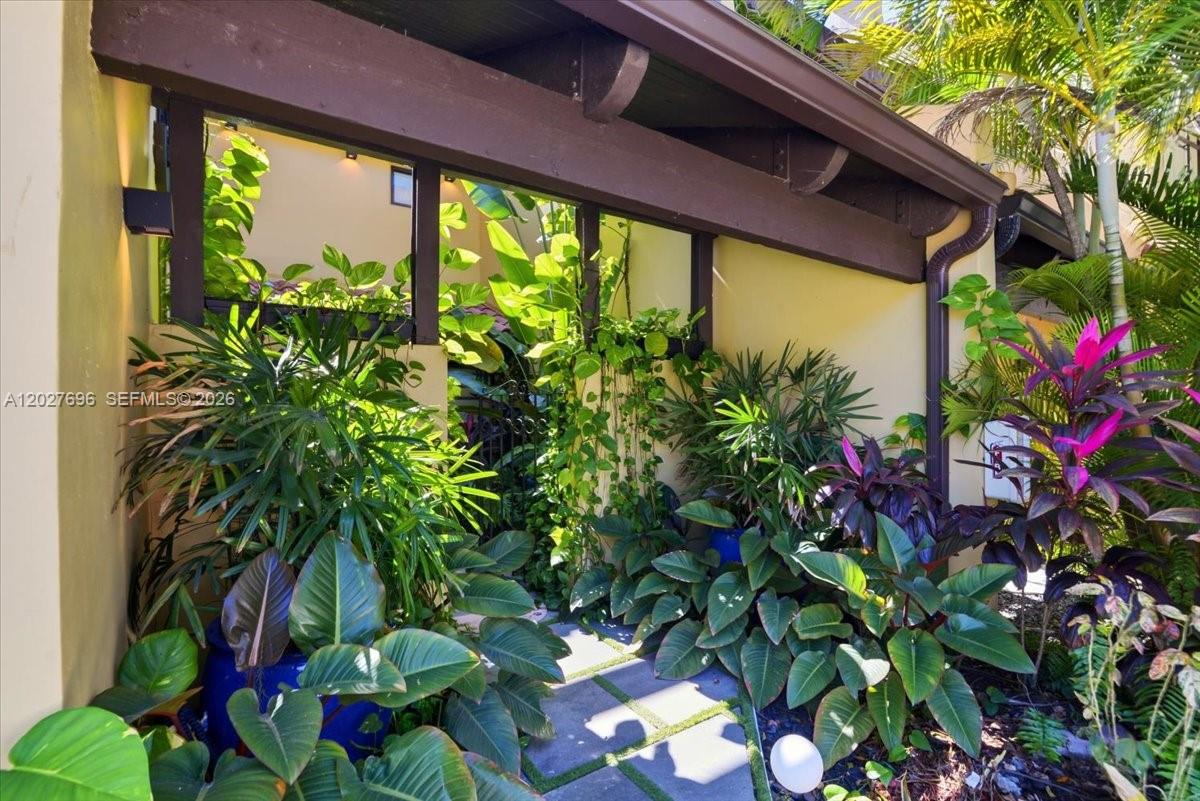 A lushly landscaped entryway features stone pavers, tropical plants, and a dark wooden pergola — 3629 Estepona Ave # 27, Doral FL 33178, DORAL, FL