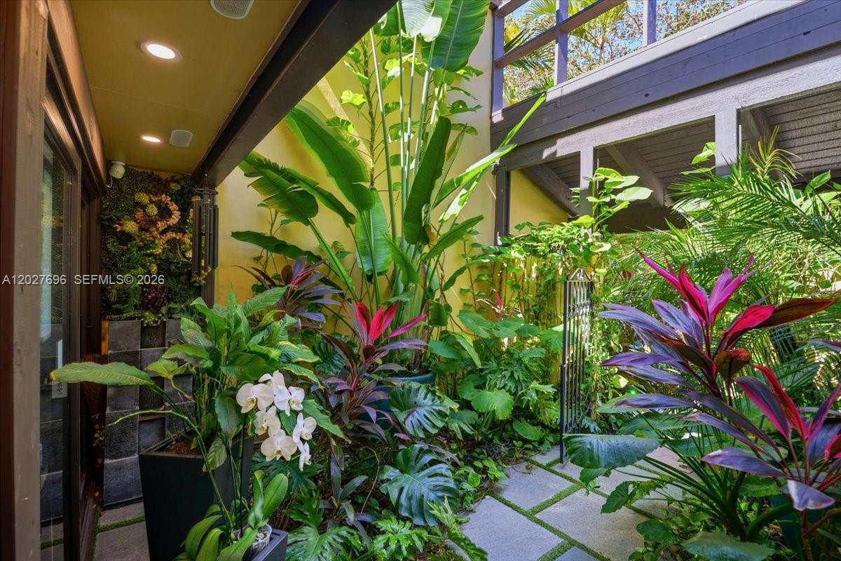 A lush, plant-filled courtyard features stone pavers, a vertical garden, and a wooden balcony — 3629 Estepona Ave # 27, Doral FL 33178, DORAL, FL