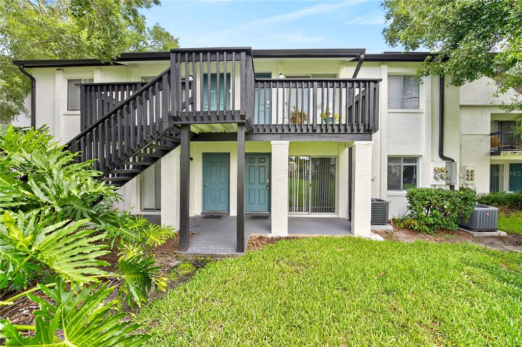 Exterior view of a two-story apartment building with a wooden staircase and balcony — 4203 S. SEMORAN BLVD UNIT 12, ORLANDO, FL