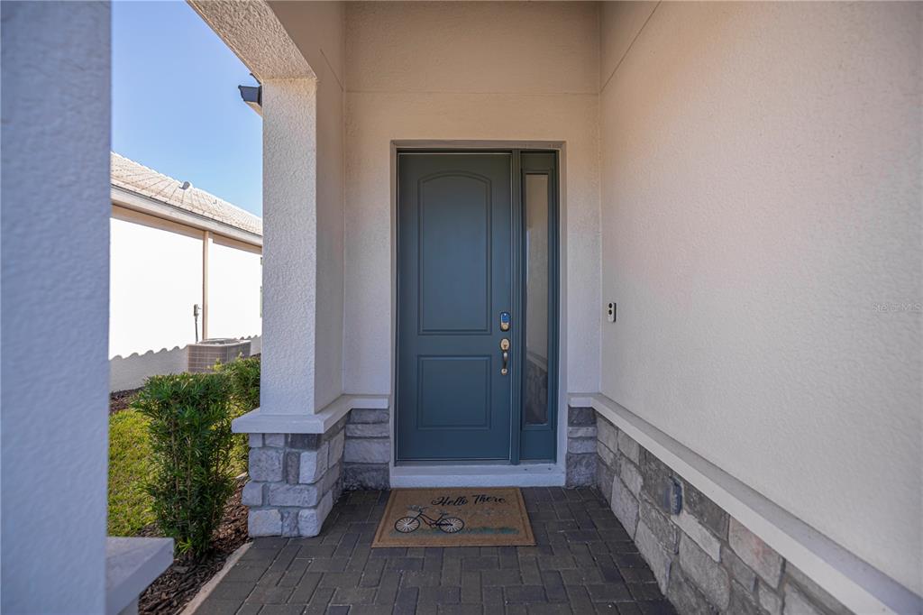 A front entryway features a dark blue door with a side light and stone accents — 19890 MONTENERO WAY, VENICE, FL