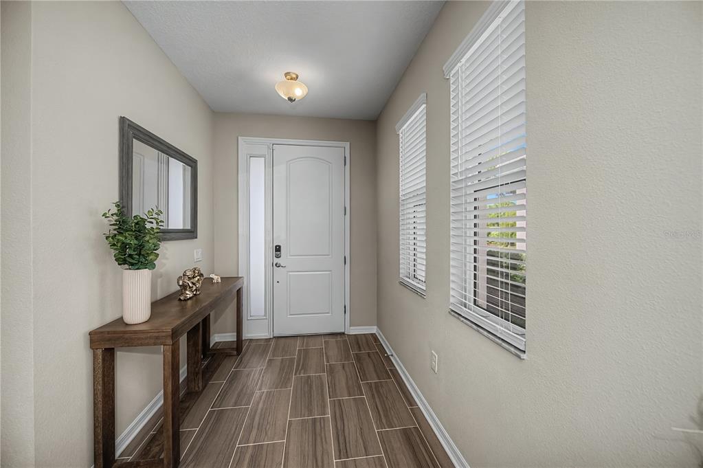 An entryway features wood-look tile flooring, a console table, a mirror, and a front door — 19890 MONTENERO WAY, VENICE, FL