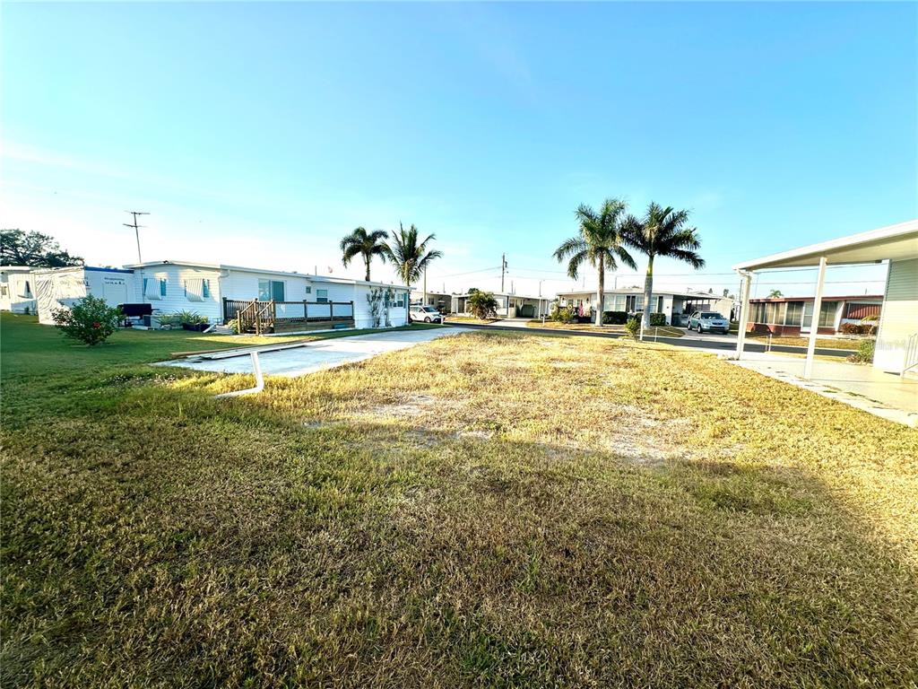 A vacant, grassy residential lot sits between two manufactured homes under a clear blue sky — 522 CENTRE STREET, PALMETTO, FL