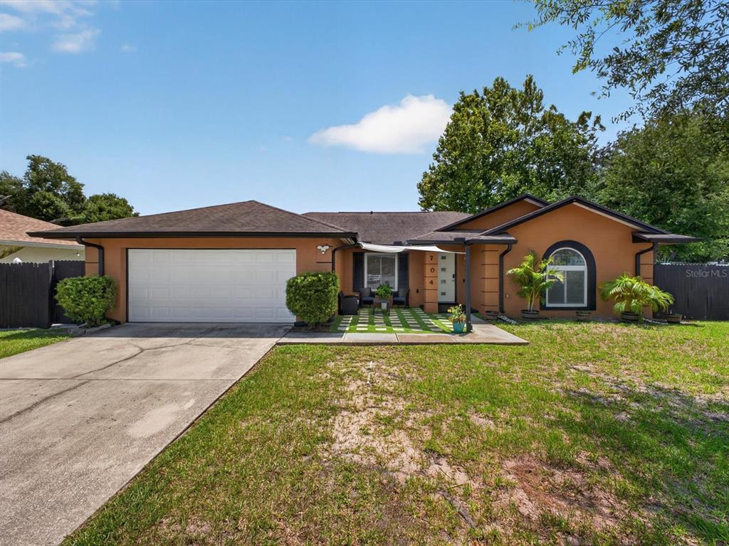 A single-story house with a two-car garage, a tan stucco exterior, and a front patio — 2704 MUSCATELLO STREET, ORLANDO, FL