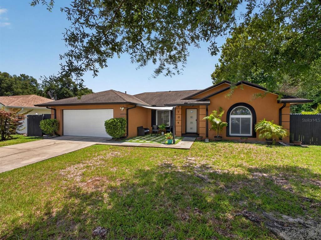 A single-story house with an orange stucco exterior, a two-car garage, and a front patio — 2704 MUSCATELLO STREET, ORLANDO, FL