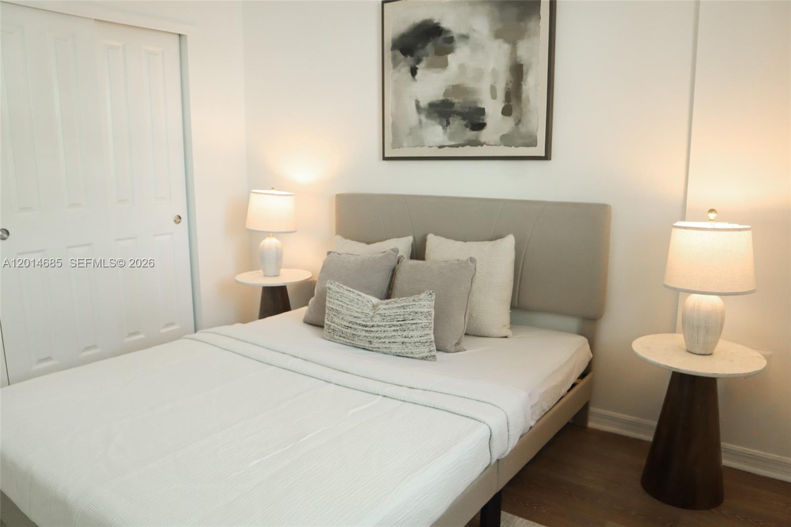 A bedroom features a bed with a neutral headboard, two side tables, and abstract wall art — 9172 Collins Ave # 212, Surfside FL 33154, SURFSIDE, FL