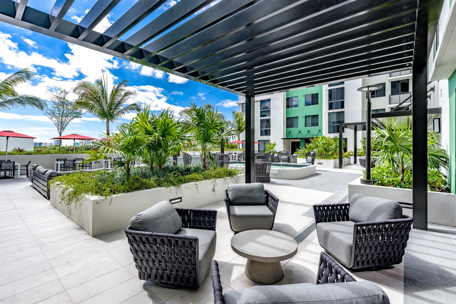 An outdoor rooftop patio features modern lounge chairs, a circular table, and lush planters — 450 SW 5th Street # 515, Miami FL 33130, MIAMI, FL