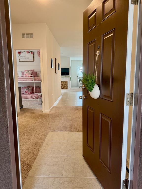 An open front door reveals a tiled entryway leading to a carpeted hallway and bedroom — 1817 SUNDANCE CHASE ROAD, MINNEOLA, FL