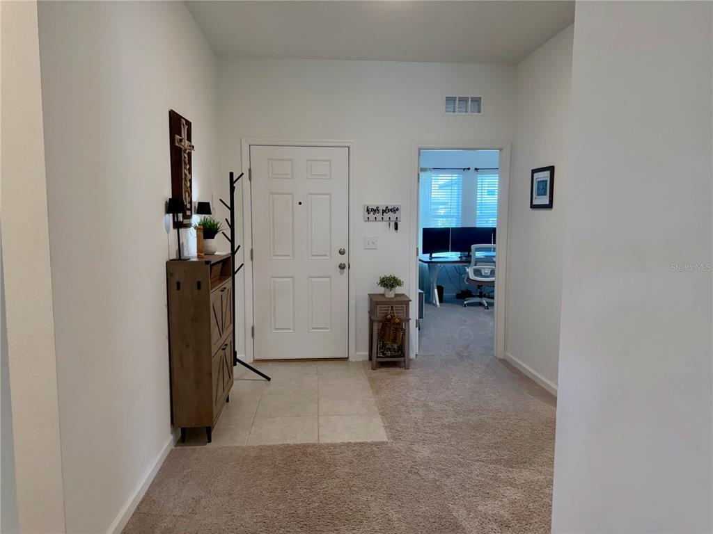 An entryway with tile flooring, a wooden shoe cabinet, a coat rack, and a doorway — 1817 SUNDANCE CHASE ROAD, MINNEOLA, FL