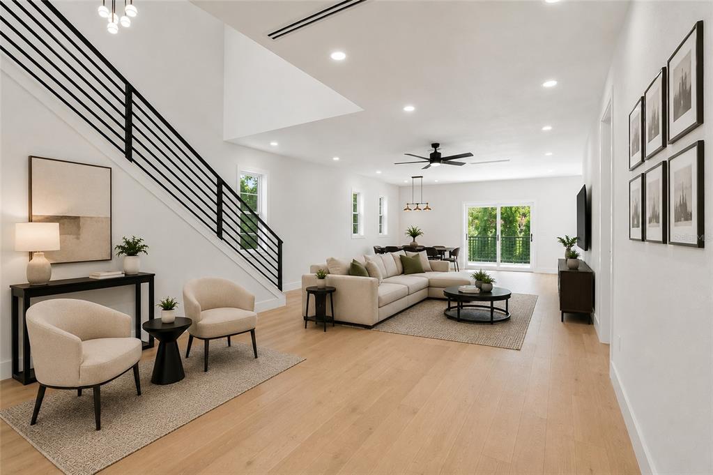 A bright, open-concept living room features light wood floors, a staircase, and modern neutral furniture — 2501 QUINCY STREET S, ST PETERSBURG, FL