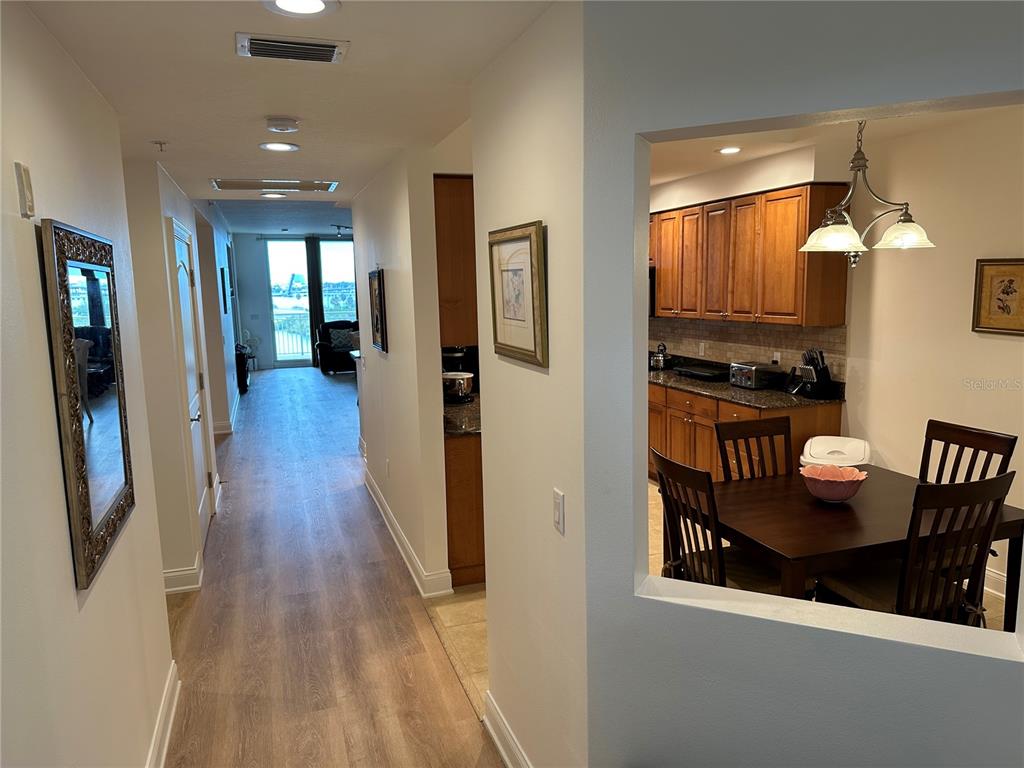 A hallway leads to a living area with a balcony, adjacent to a dining room — 615 RIVIERA DUNES WAY UNIT 406, PALMETTO, FL