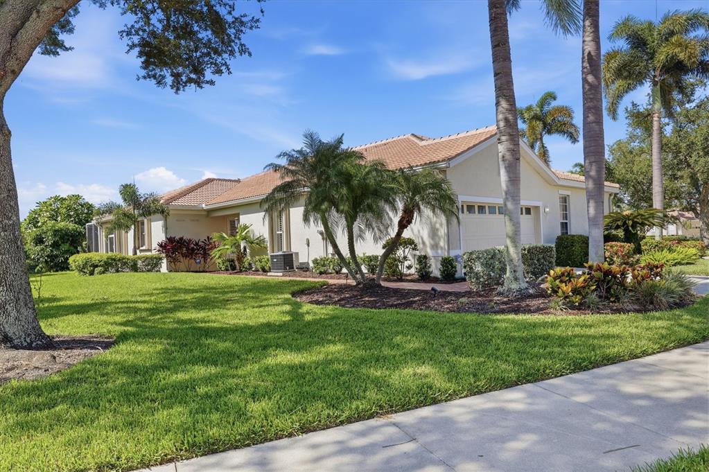 A single-story house with a tiled roof, palm trees, and a green lawn — 8050 VICTORIA FALLS CIRCLE, SARASOTA, FL