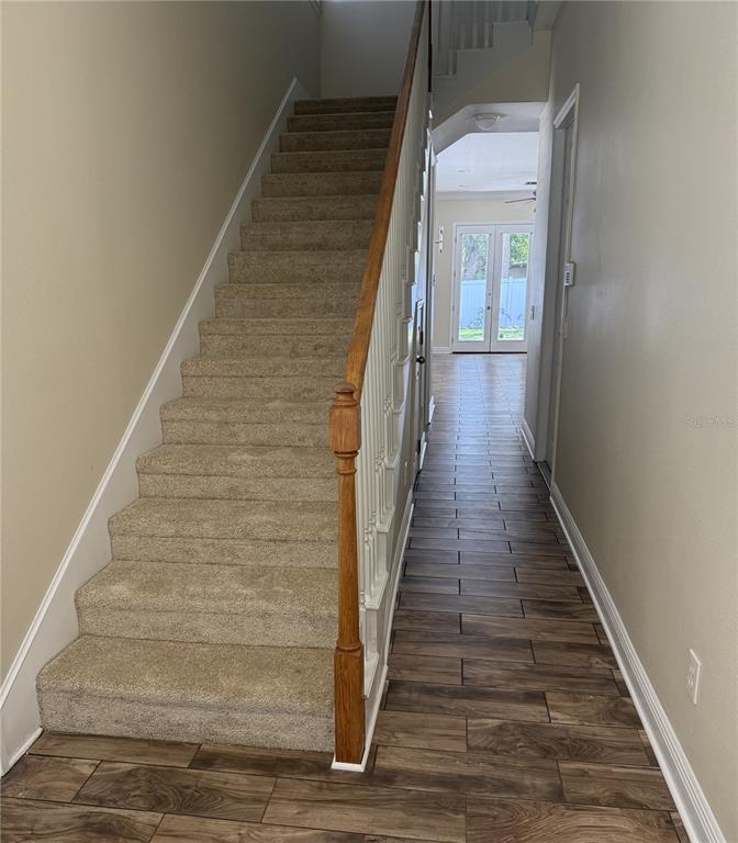An entryway features a carpeted staircase with a wooden banister beside a wood-look tiled hallway — 2618 E CENTRAL BOULEVARD, ORLANDO, FL
