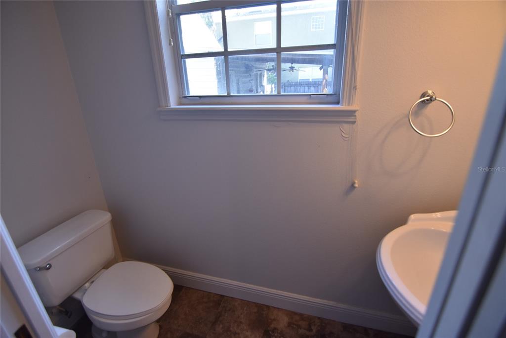 A small bathroom features a white toilet, a pedestal sink, and a window — 2618 E CENTRAL BOULEVARD, ORLANDO, FL